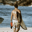 a man carrying a surfboard on a beach